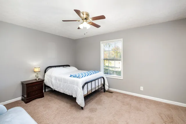 a bedroom with a bed next to a window and a chandelier