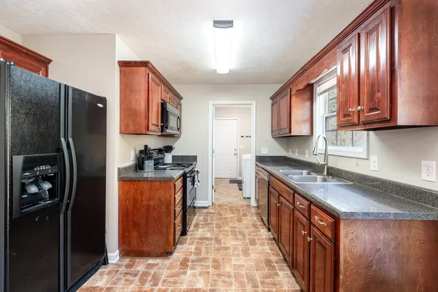 a kitchen with stainless steel appliances granite countertop a stove a refrigerator a sink and dishwasher