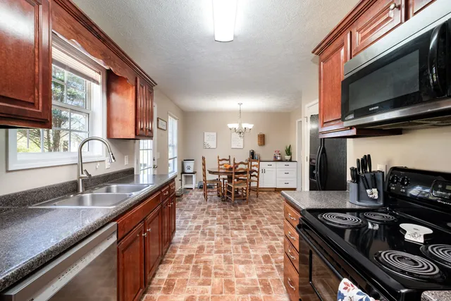 a kitchen with stainless steel appliances granite countertop a stove a sink and a microwave