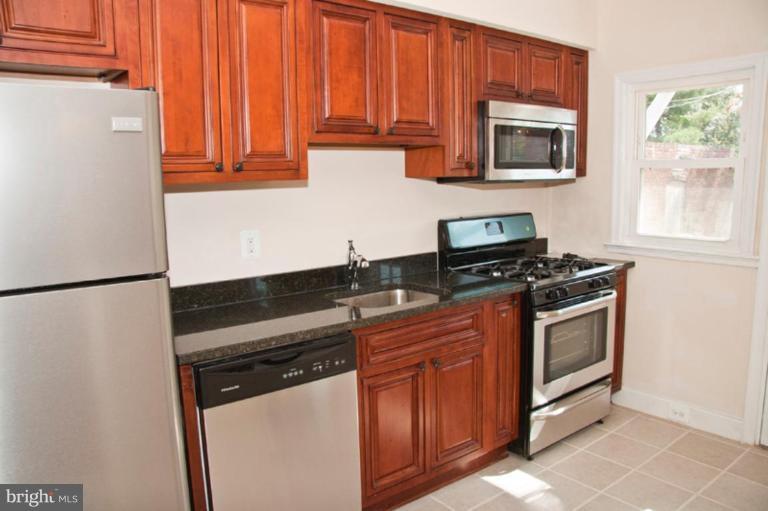 1303 Crofton Road Baltimore, MD 21239 - Photo 4 of 17 a kitchen with granite countertop a refrigerator stove and microwave