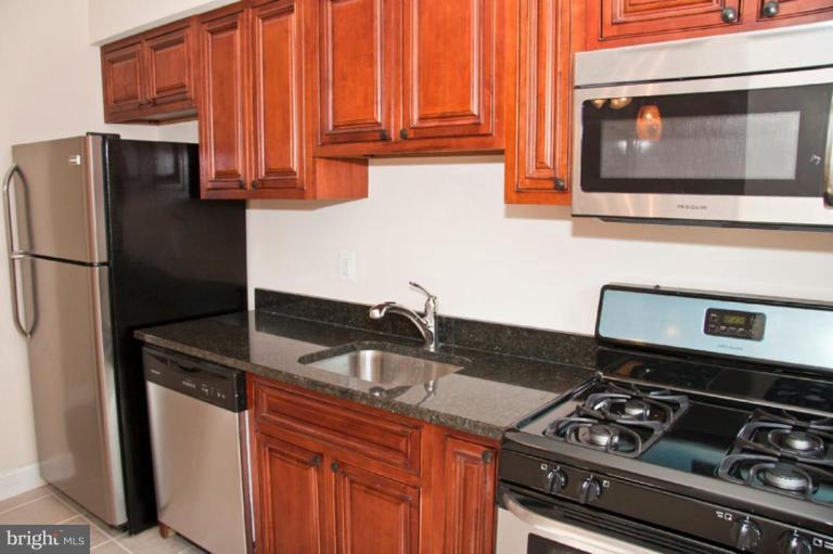 1303 Crofton Road Baltimore, MD 21239 - Photo 6 of 17 a kitchen with granite countertop a stove and a refrigerator
