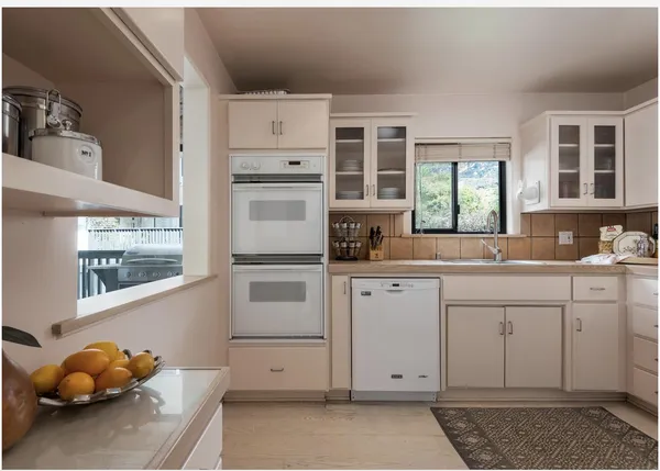 a kitchen with white cabinets and window