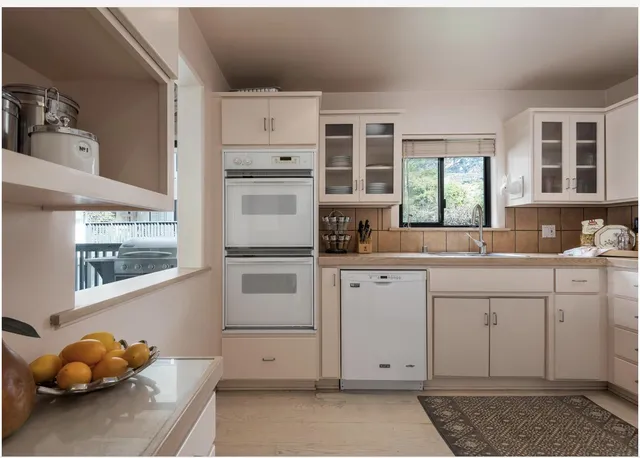 a kitchen with white cabinets and window