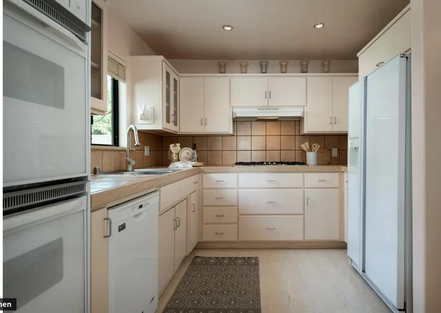 a kitchen with white cabinets and white appliances