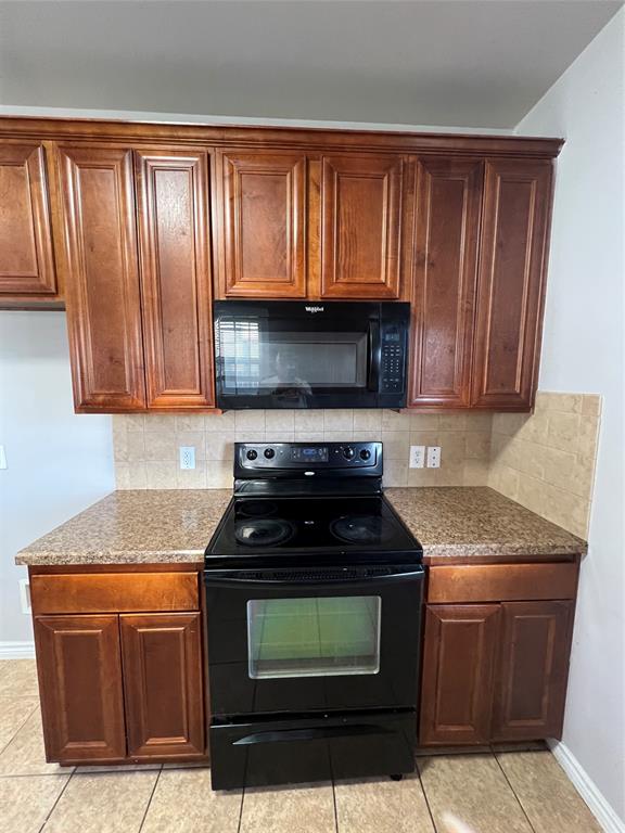 906 Parkplace Ridge Princeton, TX 75407 - Photo 18 of 25 Compact kitchen featuring rich wood cabinetry with raised-panel doors, granite-style countertops, and black electric range with viewing window