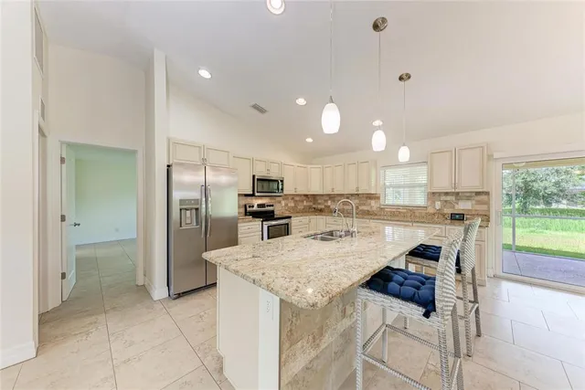 a large kitchen with stainless steel appliances granite countertop a sink and a refrigerator