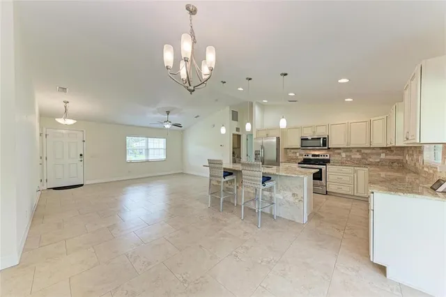 an empty room with chandelier fan and windows