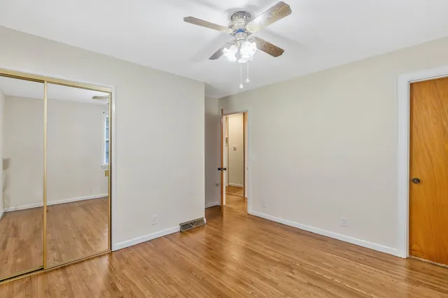 an empty room with wooden floor and a ceiling fan