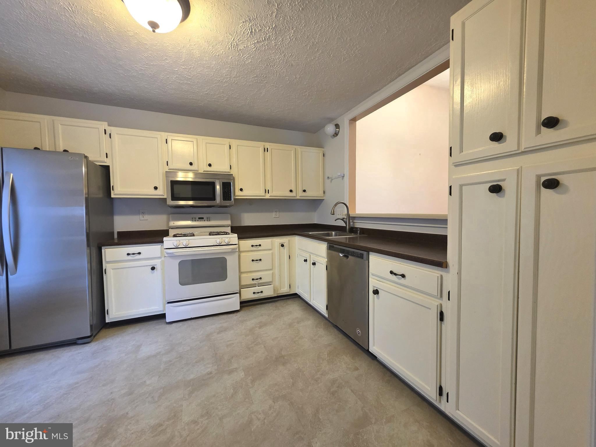 58 Windbrooke Circle, Unit 58 Gaithersburg, MD 20879 - Photo 9 of 28 a kitchen with white cabinets and white appliances