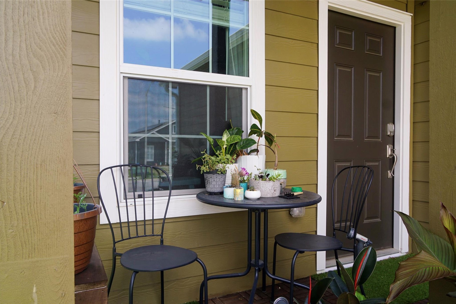 2321 Forgetmenot Lane Manor, TX 78653 - Photo 2 of 27 An inviting front entrance with rich olive siding and a welcoming patio set beckons relaxation.