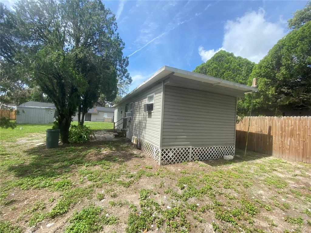 38313 Tucker Road Zephyrhills, FL 33542 - Photo 45 of 46 a backyard of a house with a large tree and wooden fence