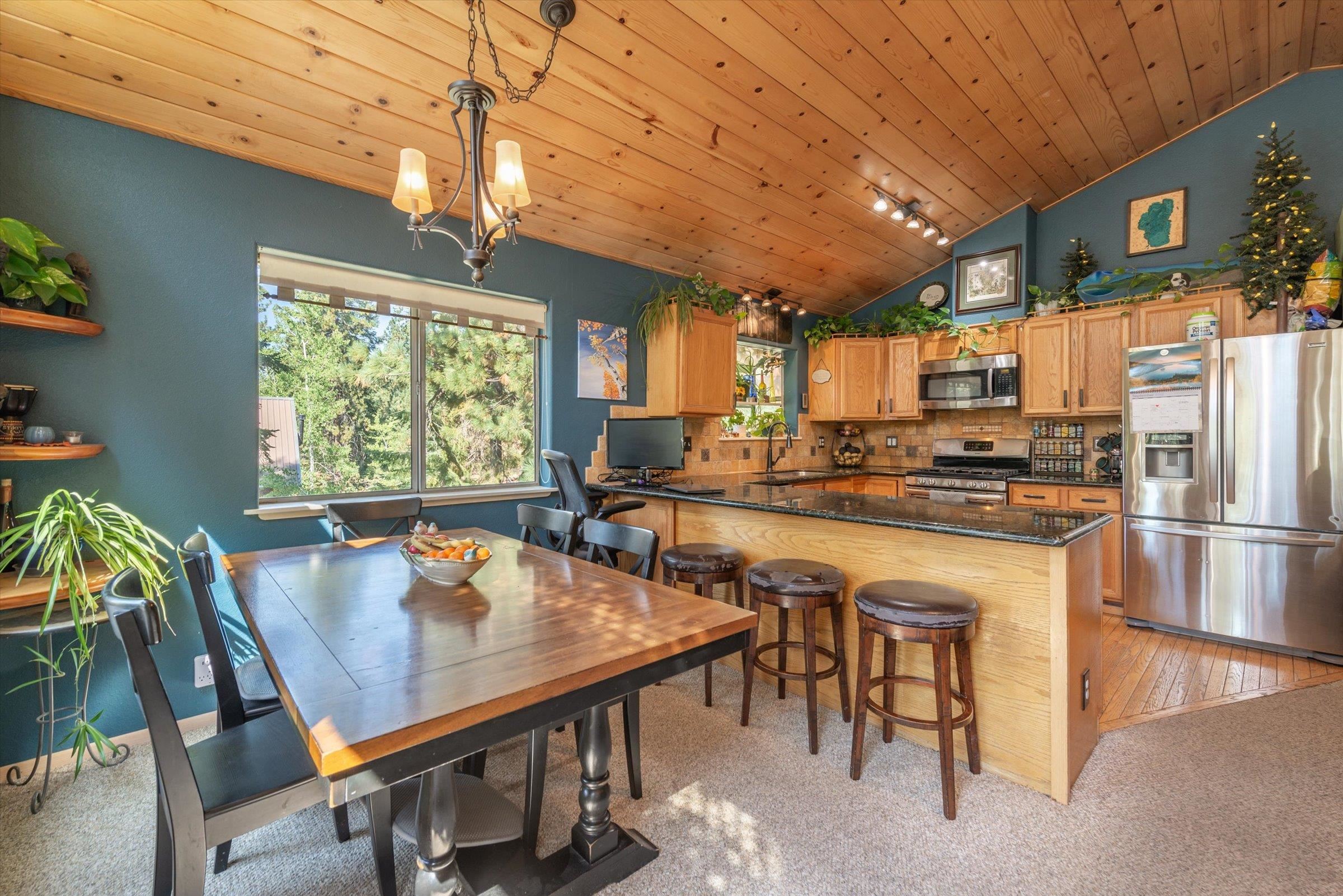 12860 Dulzura Street Truckee, CA 96161 - Photo 5 of 21 a kitchen with stainless steel appliances granite countertop a stove a refrigerator a kitchen island a table and chairs with wooden floor