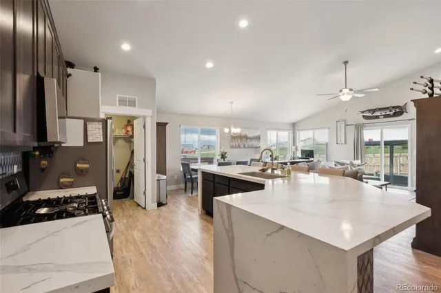 a large kitchen with stainless steel appliances a center island a stove a refrigerator cabinets and living room view