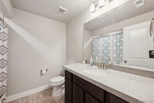a bathroom with a granite countertop sink a toilet and a mirror