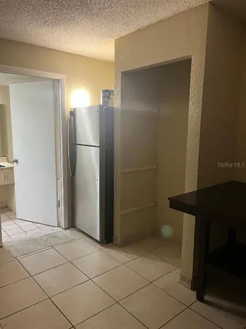 a view of a refrigerator in kitchen and an empty room