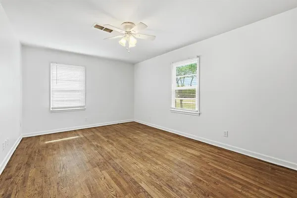 a view of an empty room with wooden floor and a window