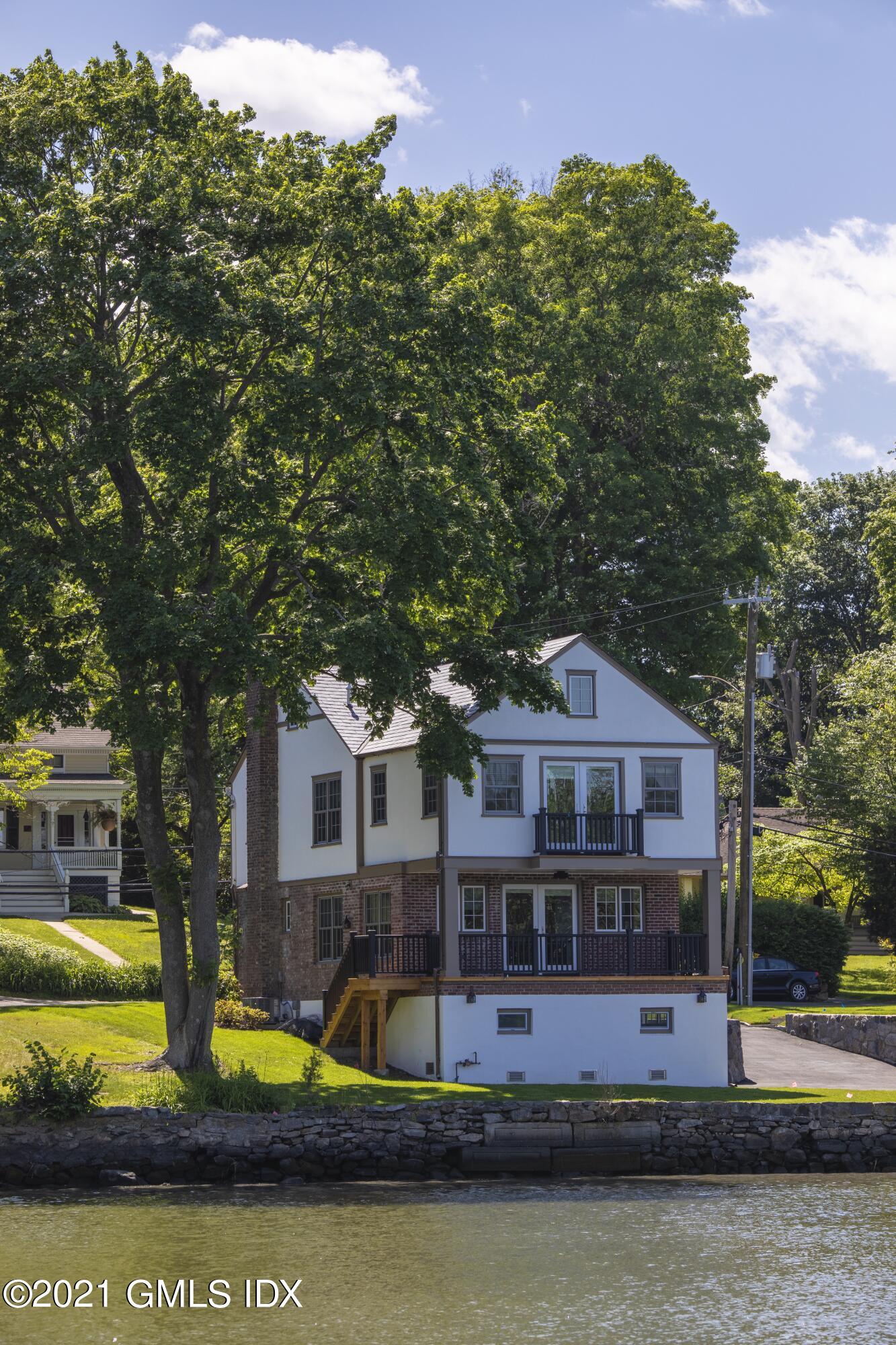 40 Strickland Road Cos Cob, CT 06807 - Photo 14 of 22 a front view of a house with swimming pool and trees
