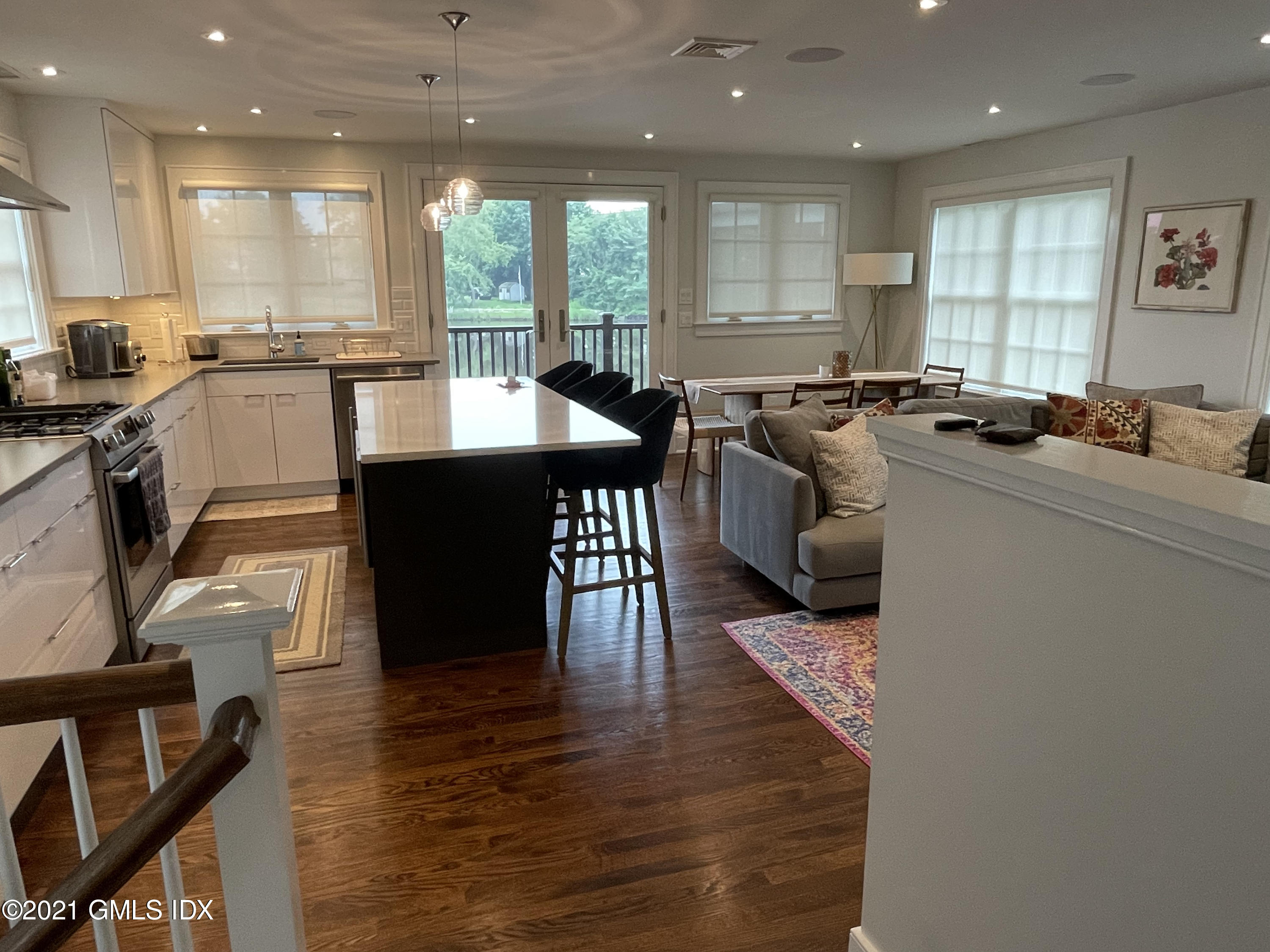 40 Strickland Road Cos Cob, CT 06807 - Photo 5 of 22 a open kitchen with stainless steel appliances granite countertop a stove a refrigerator a sink a dining table and chairs with wooden floor