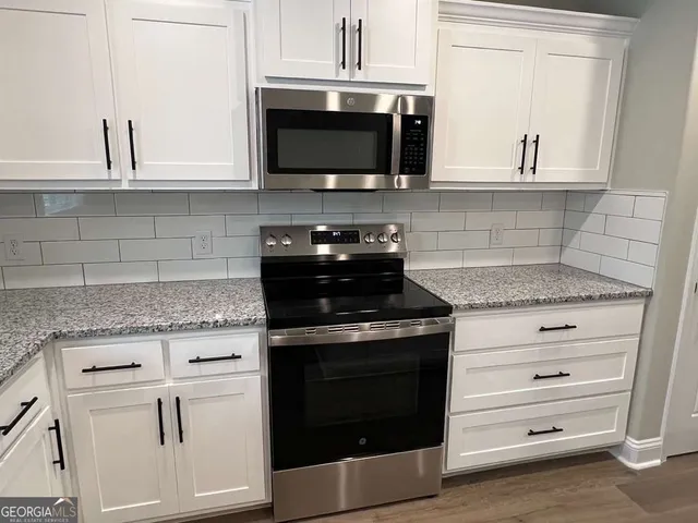 a kitchen with stainless steel appliances kitchen island granite countertop a refrigerator stove top oven and sink