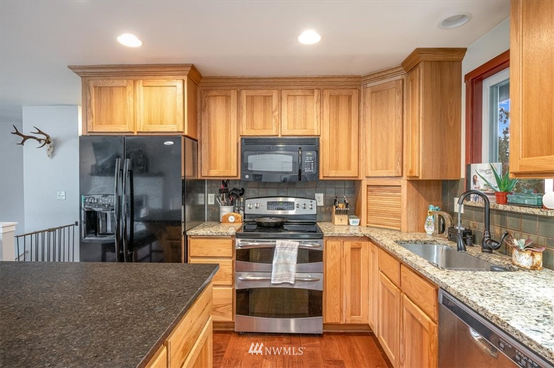 5942 Longdin Road Ferndale, WA 98248 - Photo 9 of 30 a kitchen with stainless steel appliances granite countertop a stove top oven a sink and dishwasher