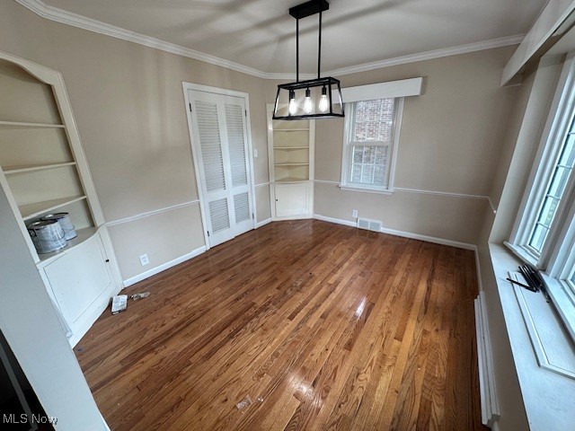 15959 Glynn Road Cleveland, OH 44112 - Photo 7 of 23 Unfurnished dining area with built in features, ornamental molding, and wood finished floors