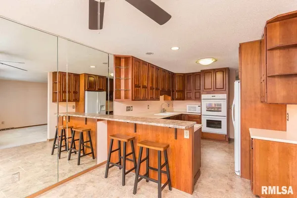 a kitchen with stainless steel appliances kitchen island granite countertop wooden cabinets and a refrigerator