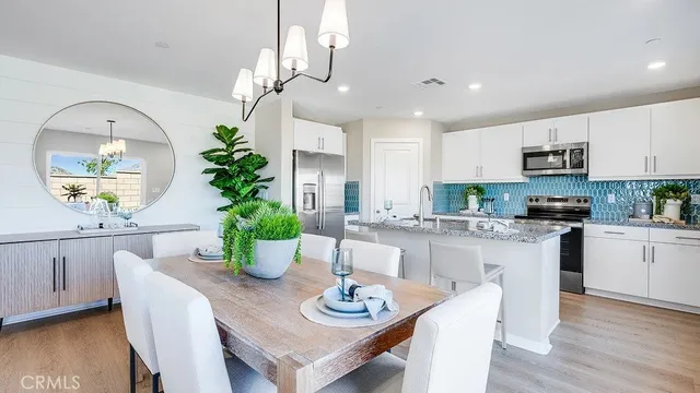 a kitchen with a dining table chairs refrigerator and microwave