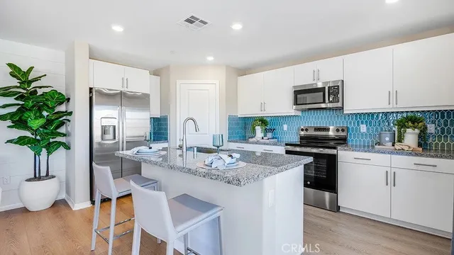 a kitchen with stainless steel appliances granite countertop a stove a sink a microwave a refrigerator and cabinets