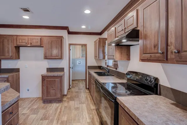 a kitchen with granite countertop a stove a sink dishwasher and a microwave oven with white cabinets