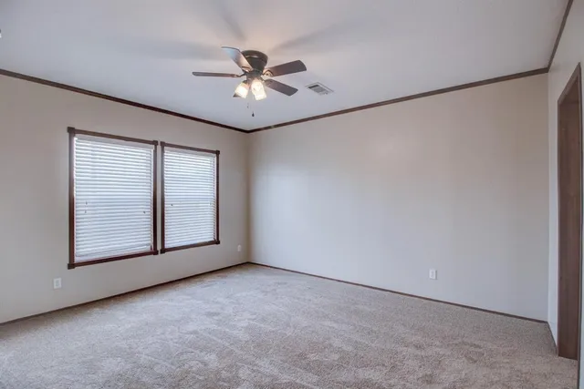 an empty room with windows and fan