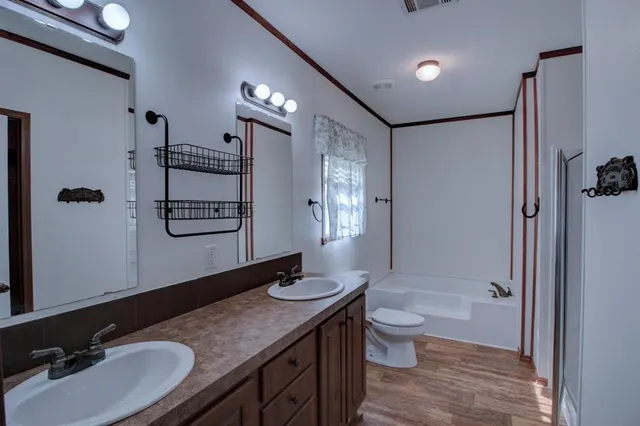 a bathroom with a granite countertop sink toilet a mirror a vanity and shower