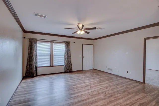 a view of an empty room with a window and wooden floor