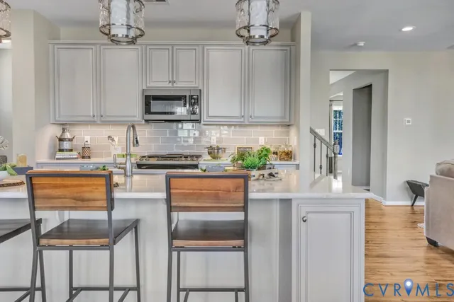 a kitchen with stainless steel appliances granite countertop a stove top oven a sink dishwasher and a refrigerator with wooden floor