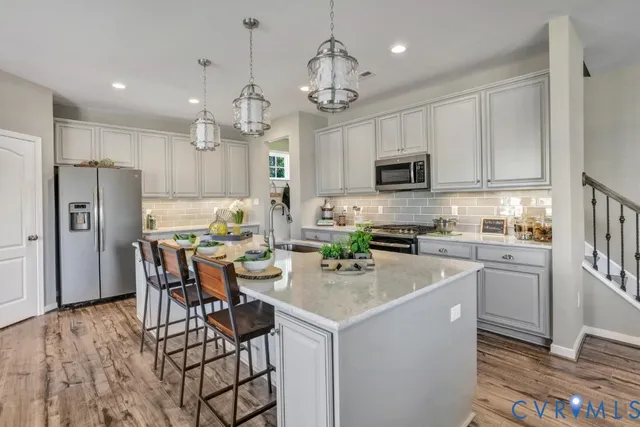 a kitchen with stainless steel appliances granite countertop a refrigerator a stove top oven a sink dishwasher and a refrigerator with wooden floor