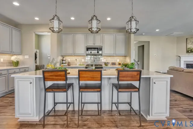 a kitchen with kitchen island granite countertop a view of living room and stainless steel appliances