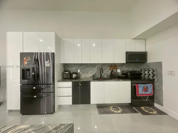 a kitchen with granite countertop a refrigerator and a stove top oven