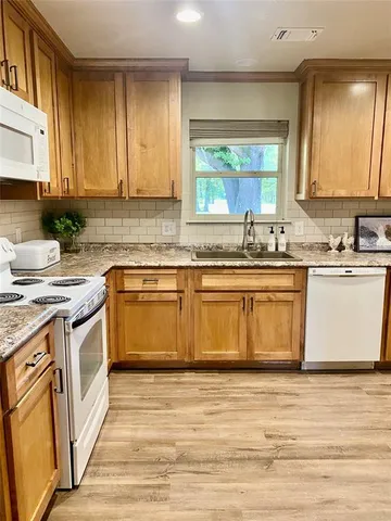 a kitchen with stainless steel appliances granite countertop a sink stove cabinets and wooden floor