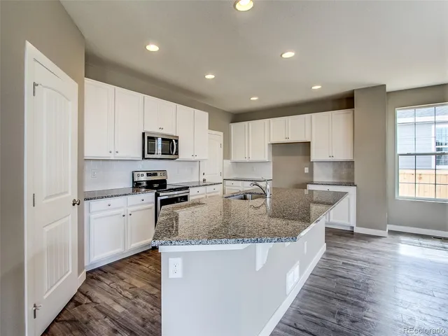 a large kitchen with granite countertop a sink dishwasher stove top oven and refrigerator