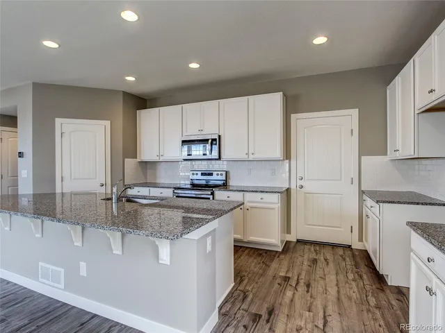 a kitchen with granite countertop white cabinets and white appliances