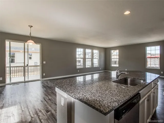 a kitchen with granite countertop a sink window and cabinets