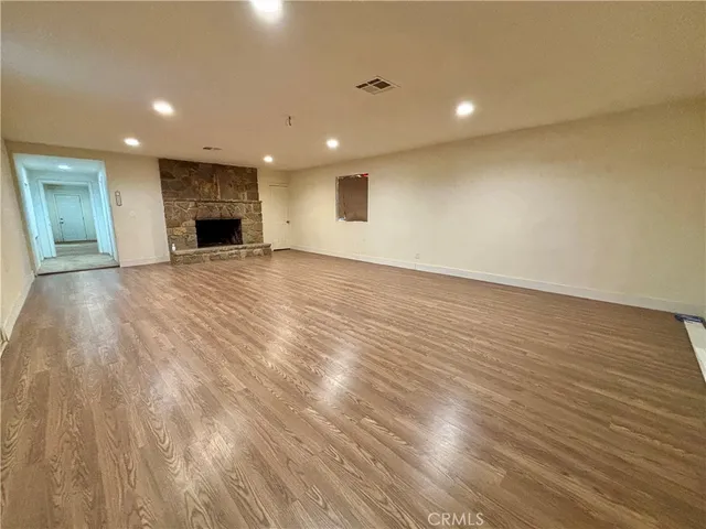 a view of empty room with wooden floor and fireplace