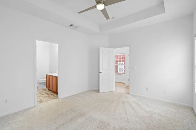 an empty room with a ceiling fan and carpet