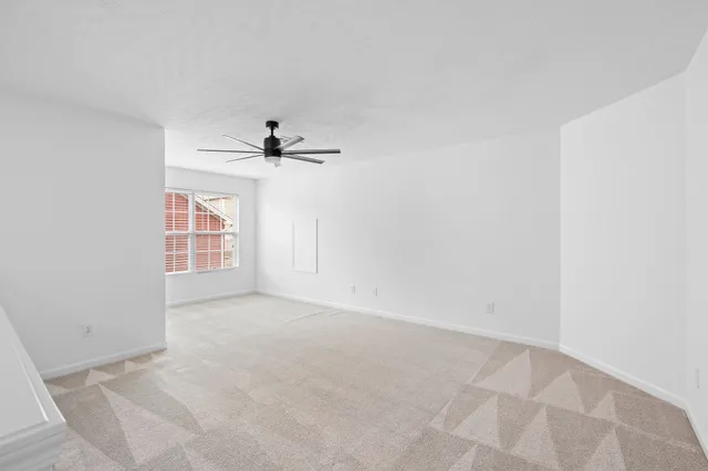an empty room with windows and ceiling fan