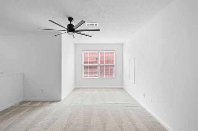 a view of a big room with windows and chandelier fan