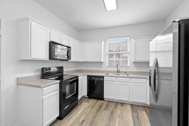 a kitchen with stainless steel appliances granite countertop white cabinets a sink a stove a refrigerator with grey cabinets