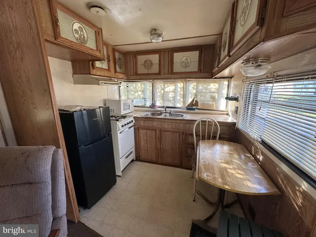 a kitchen with stainless steel appliances granite countertop a refrigerator a sink dishwasher a stove and white countertops with wooden floor