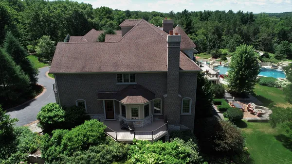 an aerial view of a house with a yard and mountain view in back