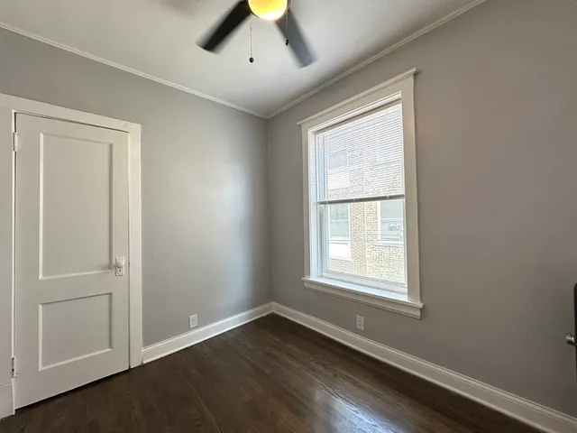an empty room with wooden floor cabinet and windows