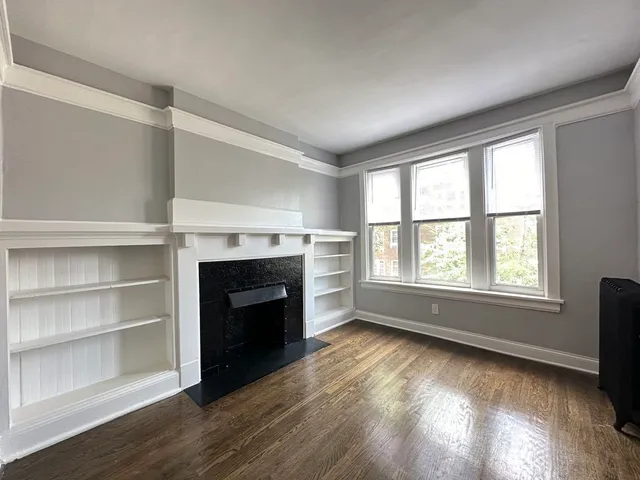 a view of an empty room with a window and fireplace