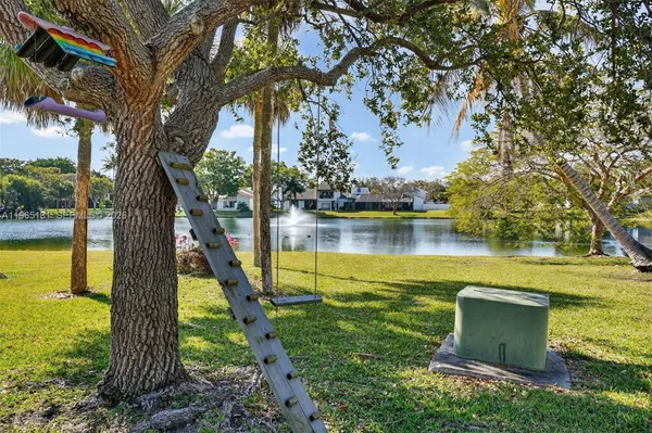 a view of a lake with a yard and a large tree
